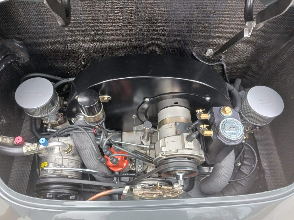 Classic car engine compartment showing various mechanical components and wiring with dual air filters visible on each side.