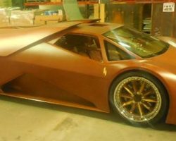 A matte brown, futuristic sports car with sharp angles is parked indoors on a concrete floor.